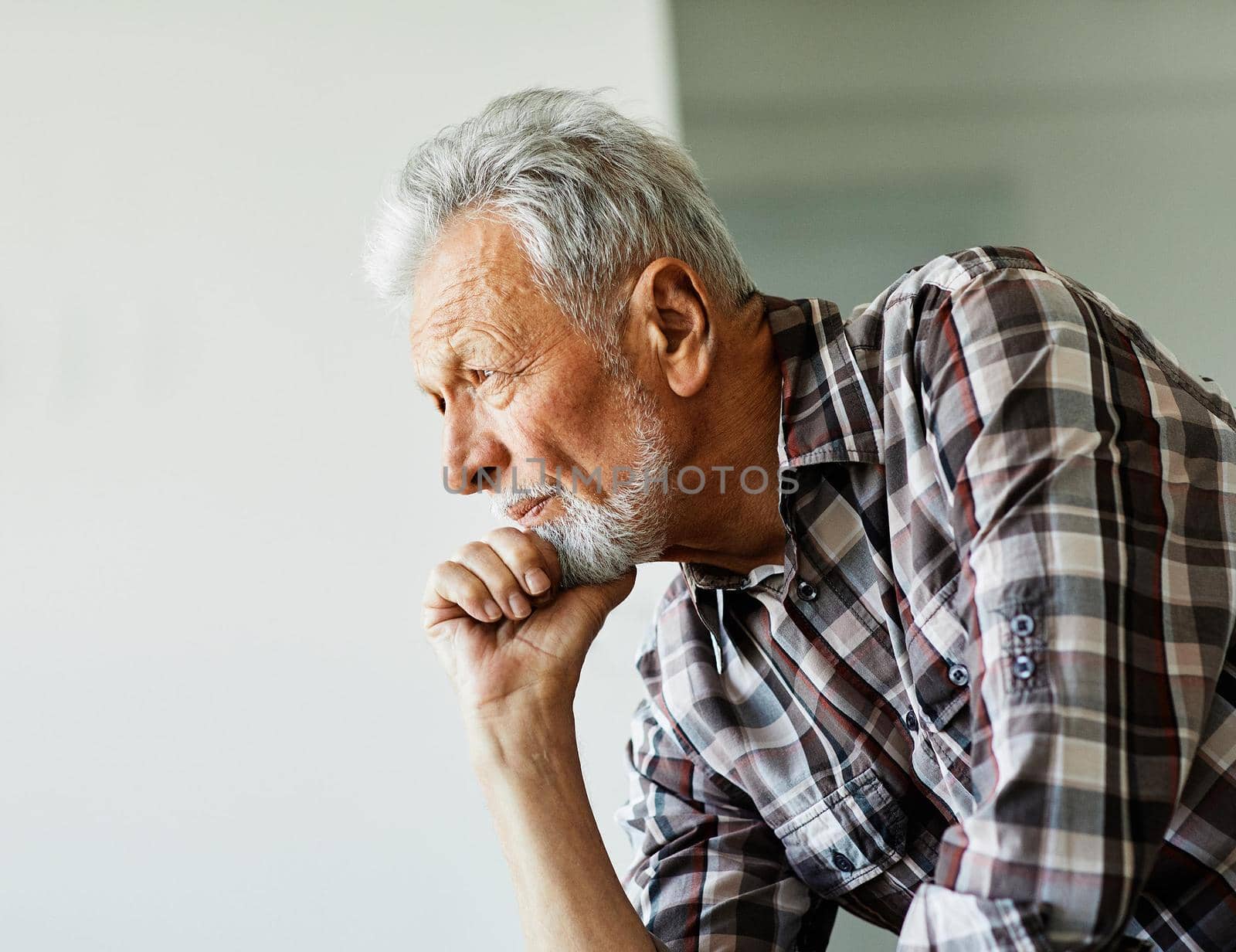 Portrait of a serious senior elderly man posing by window at home