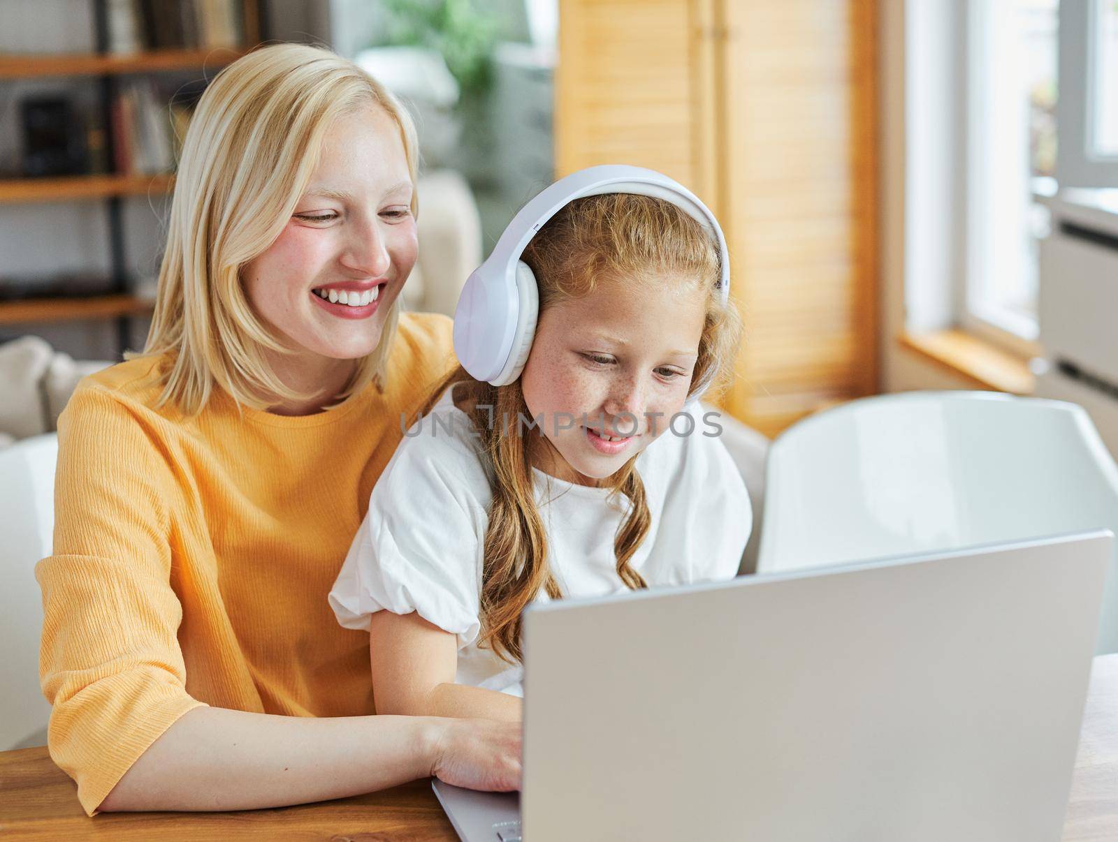 Portrait of two sisters or mother and daughter having fun together using laptop computer at home