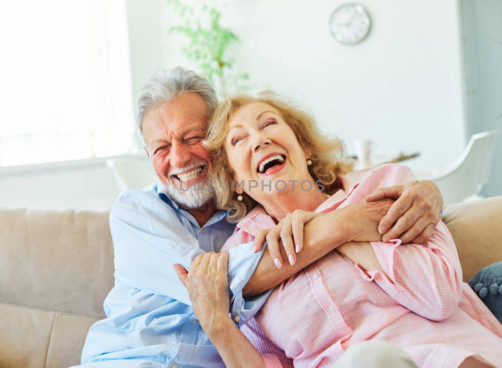Portrait of a happy senior couple embracing hugging and having fun at home