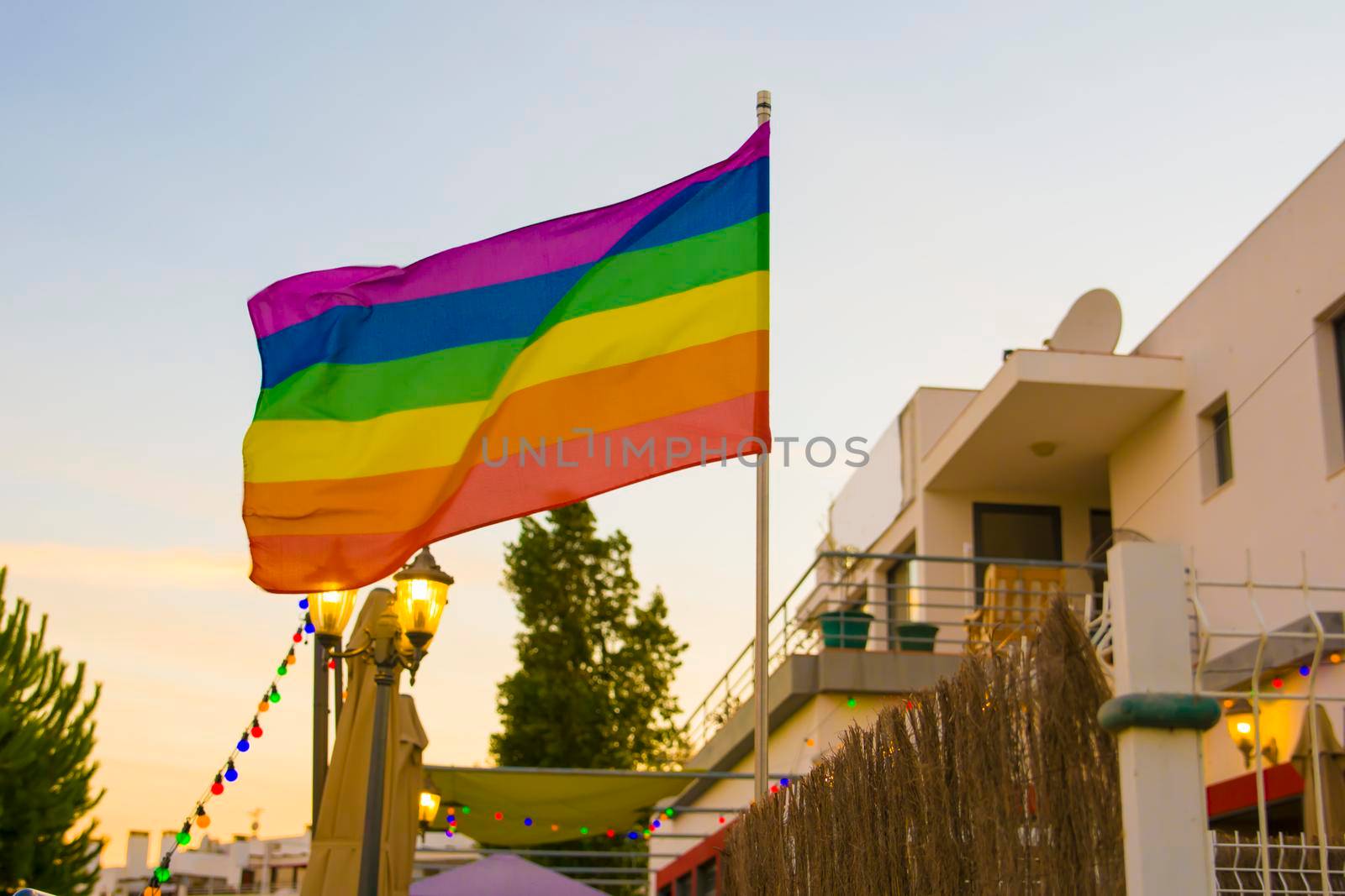 Flag lgbt against the backdrop of the setting sun in an open-air bar