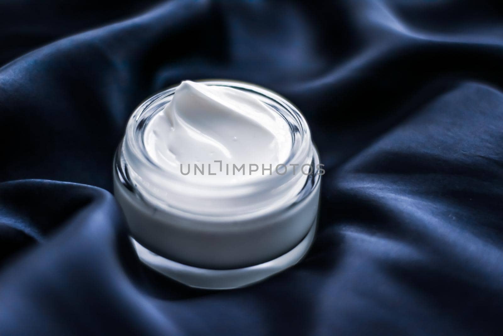 Beauty, anti-age cosmetics and skincare concept - Luxury face cream jar on a dark blue silk