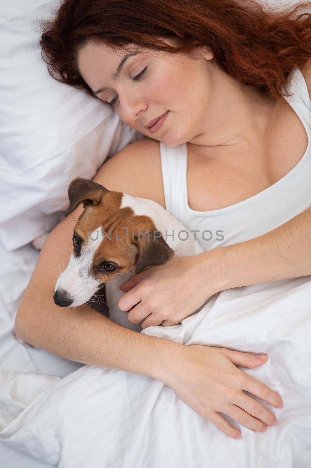 Caucasian woman is napping in bed hugging her beloved dog