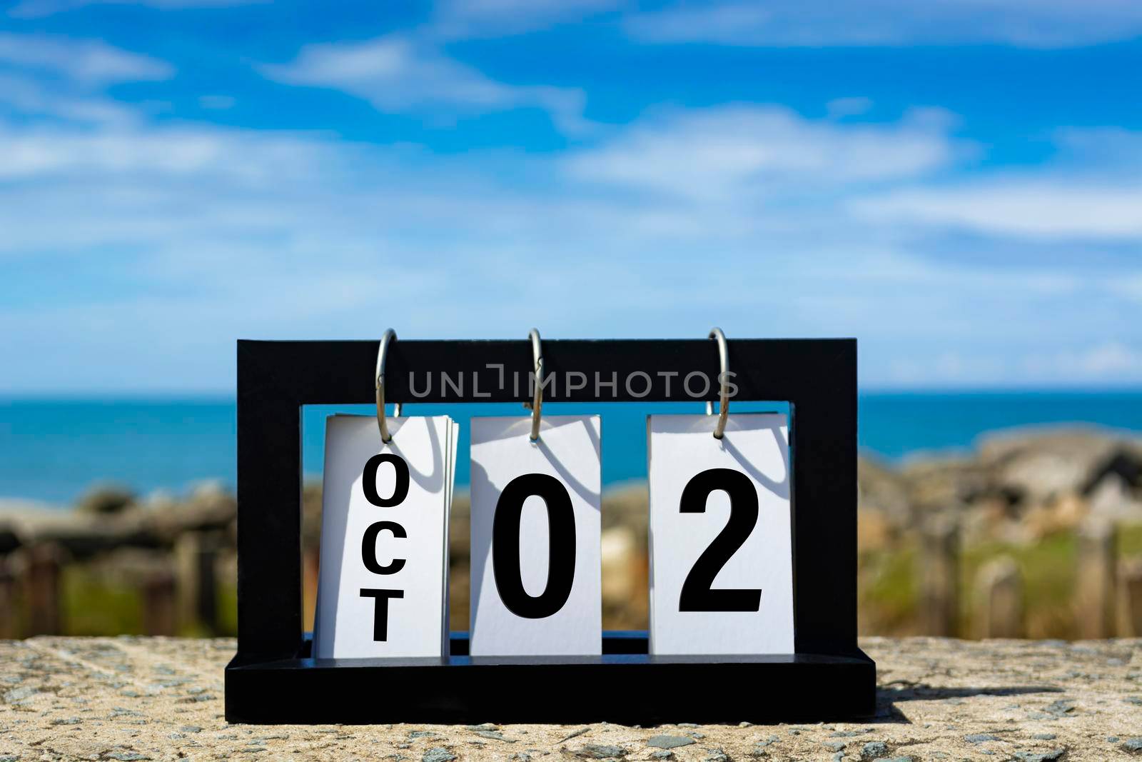 Oct 02 calendar date text on wooden frame with blurred background of ocean. Calendar date concept.