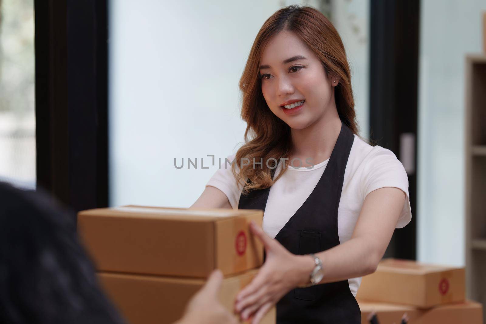 Asian woman employee freelance with parcel box for delivery to customer.