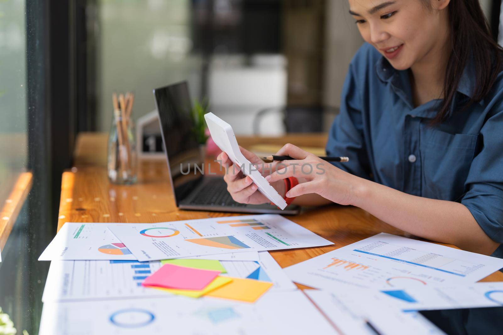 Businesswoman works on analyzing financial data using a calculator with calculations. Accounting Concepts and Personal Financial Planning.