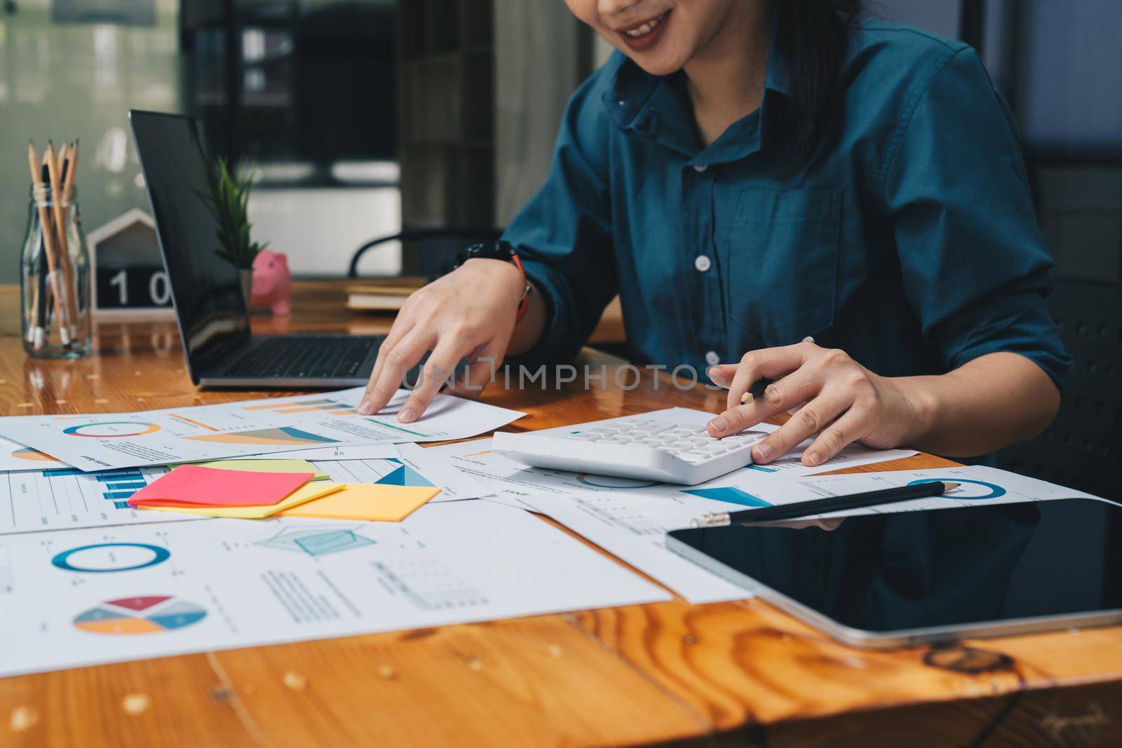 businesswoman working on desk office with using a calculator to calculate the numbers, finance accounting concept by nateemee