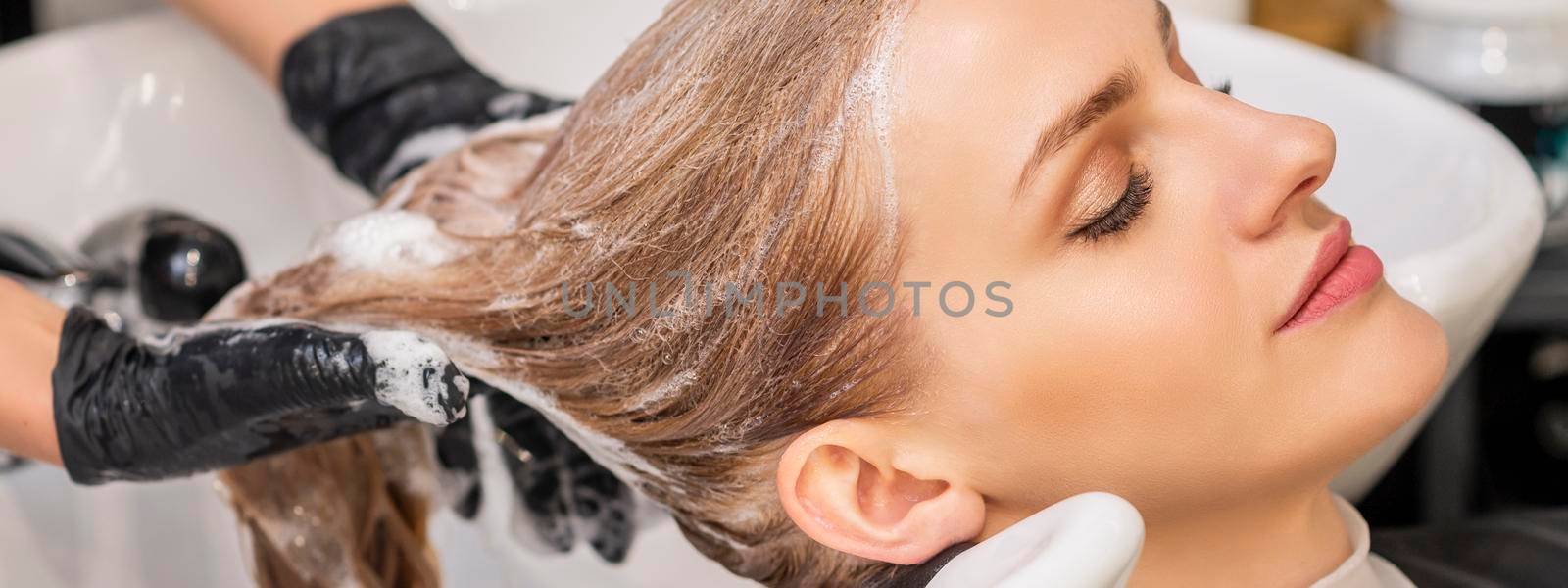 Beautiful young caucasian woman receiving wash her hair in a hair salon