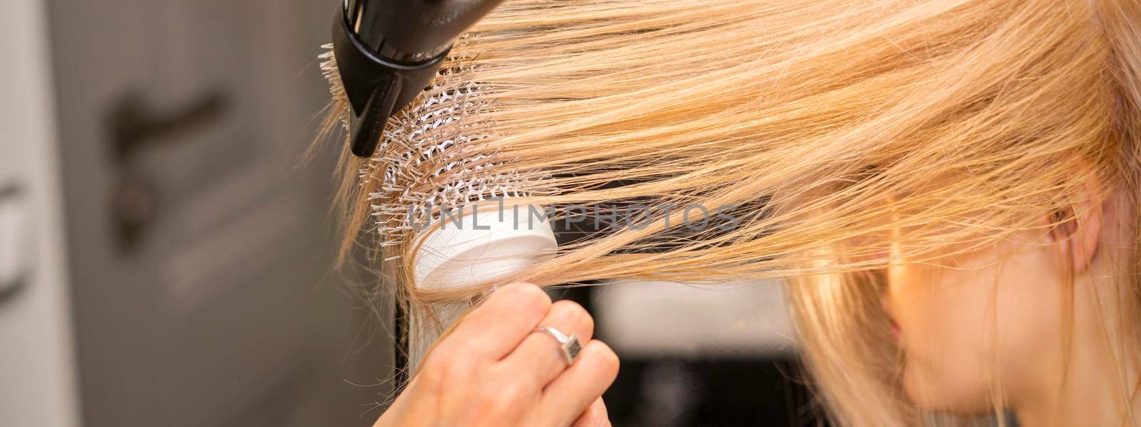 Hand drying hair of woman by okskukuruza