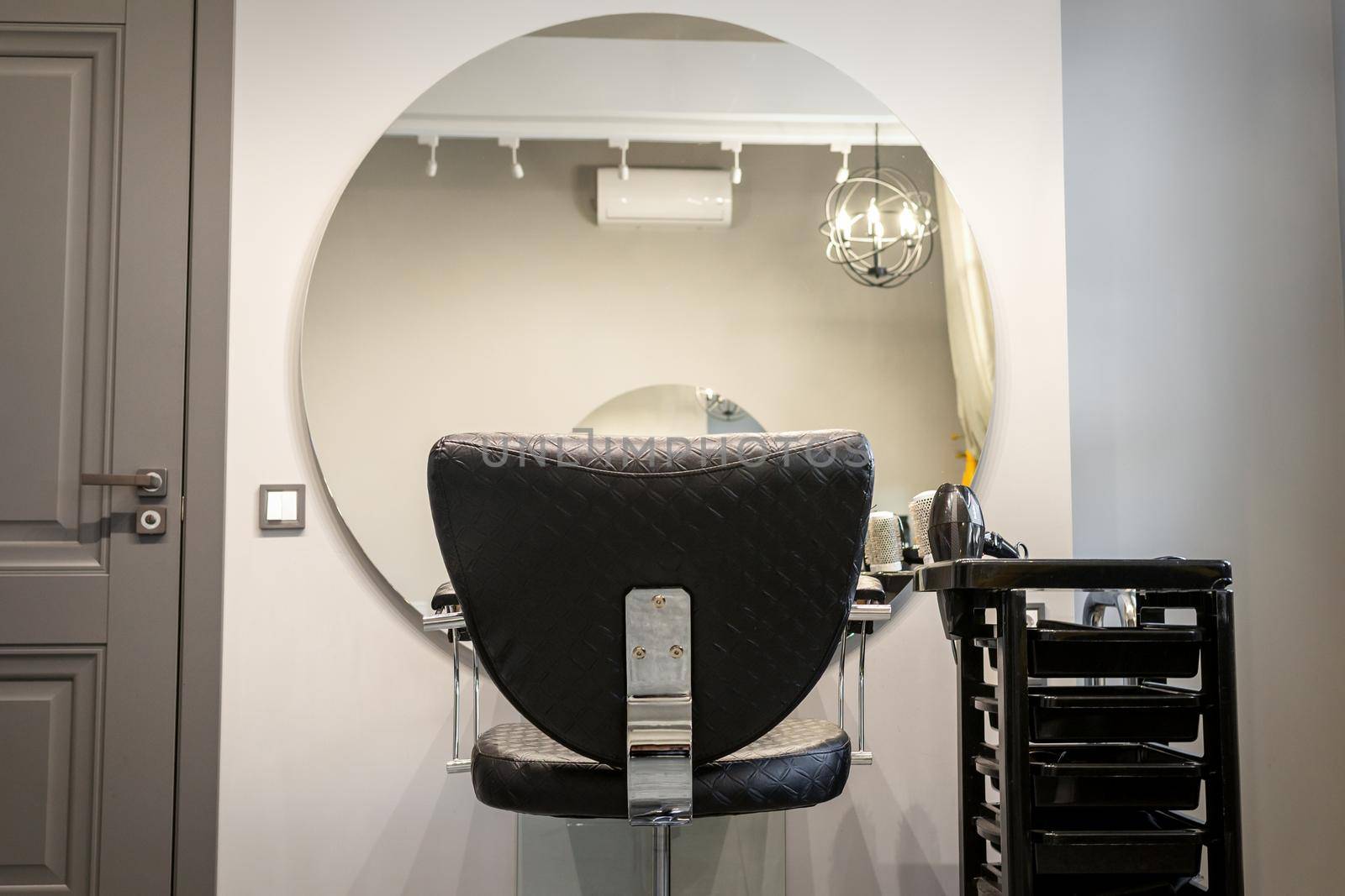 Interior of a beauty salon. Black leather chair in front of the mirror in the beauty salon. Interior of a beauty salon