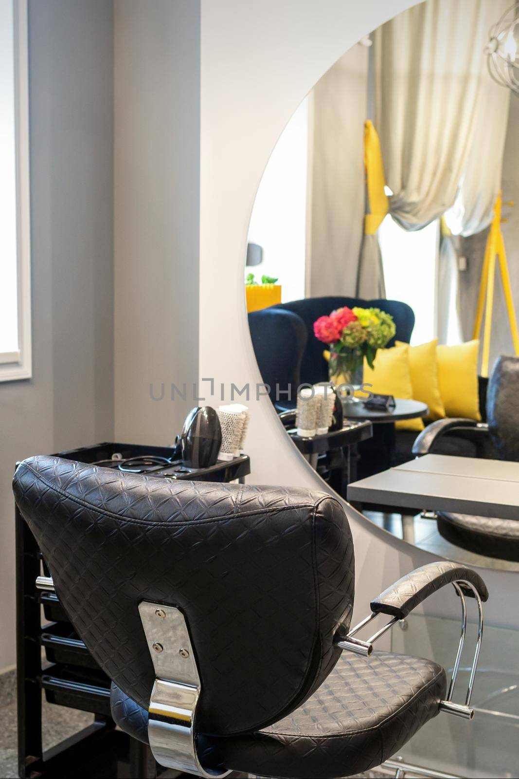 Interior of a beauty salon. Black leather chair in front of the mirror in the beauty salon. Interior of a beauty salon