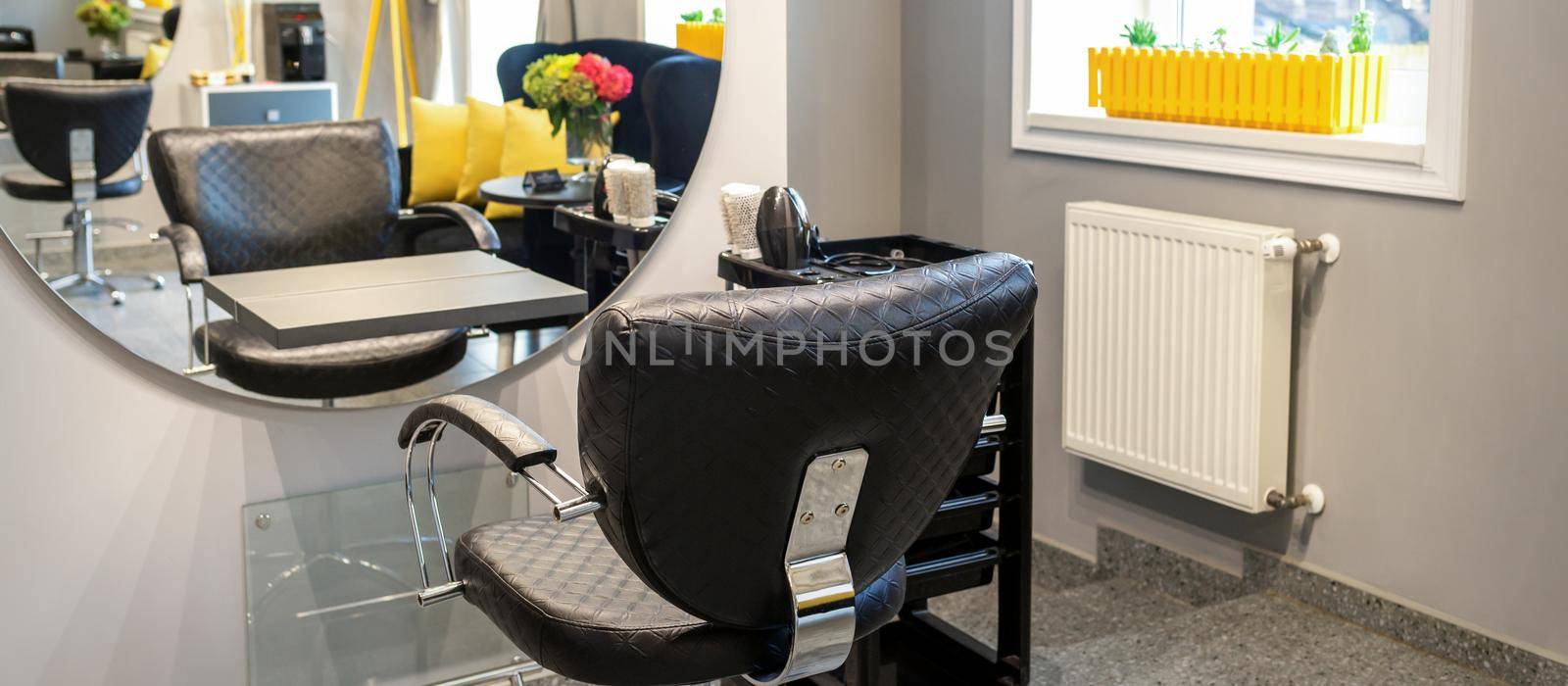 Interior of a beauty salon. Black leather chair in front of the mirror in the beauty salon. Interior of a beauty salon