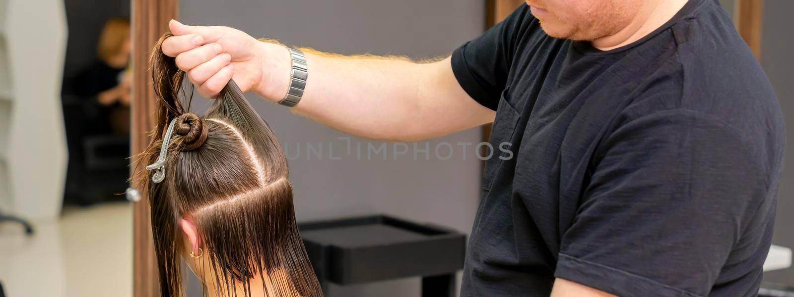 Male hairdresser splits long hair by okskukuruza