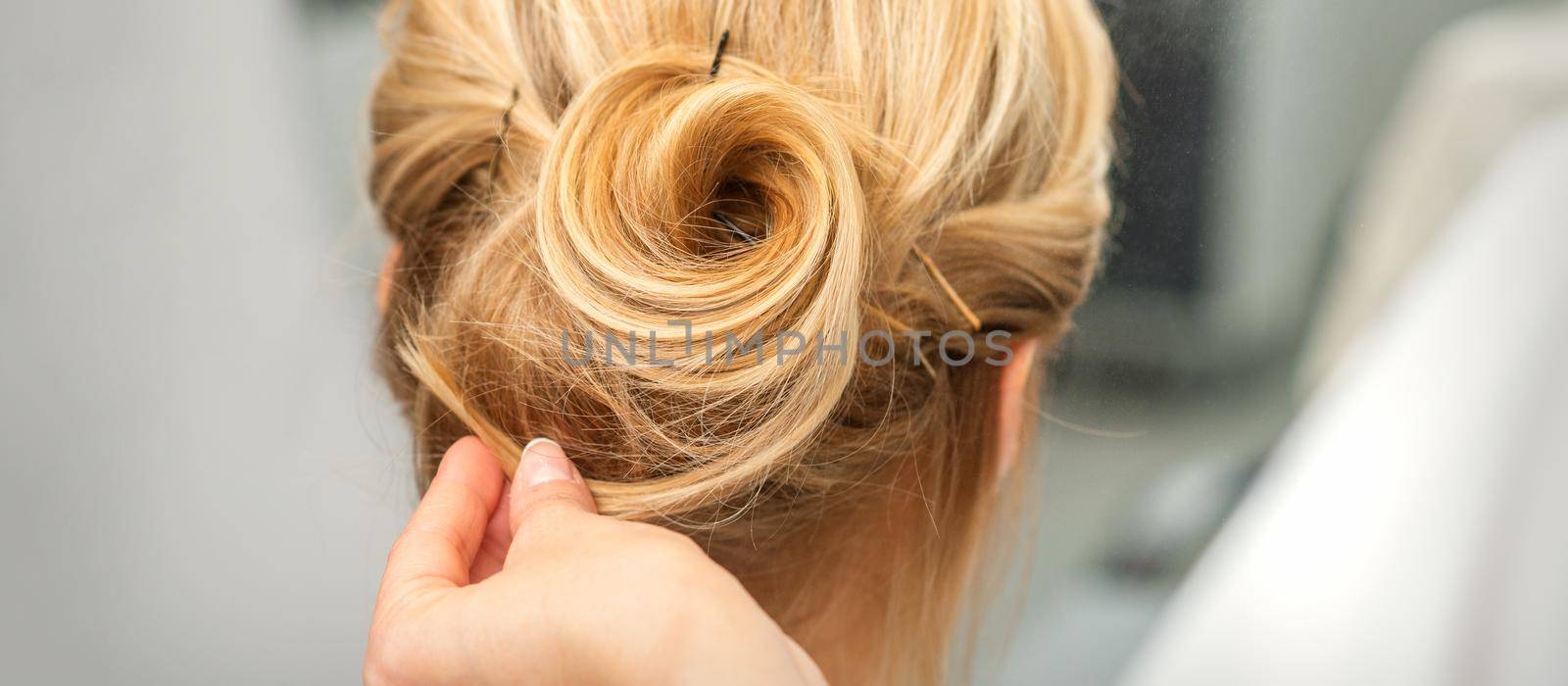 Female hairdresser styling blonde hair by okskukuruza
