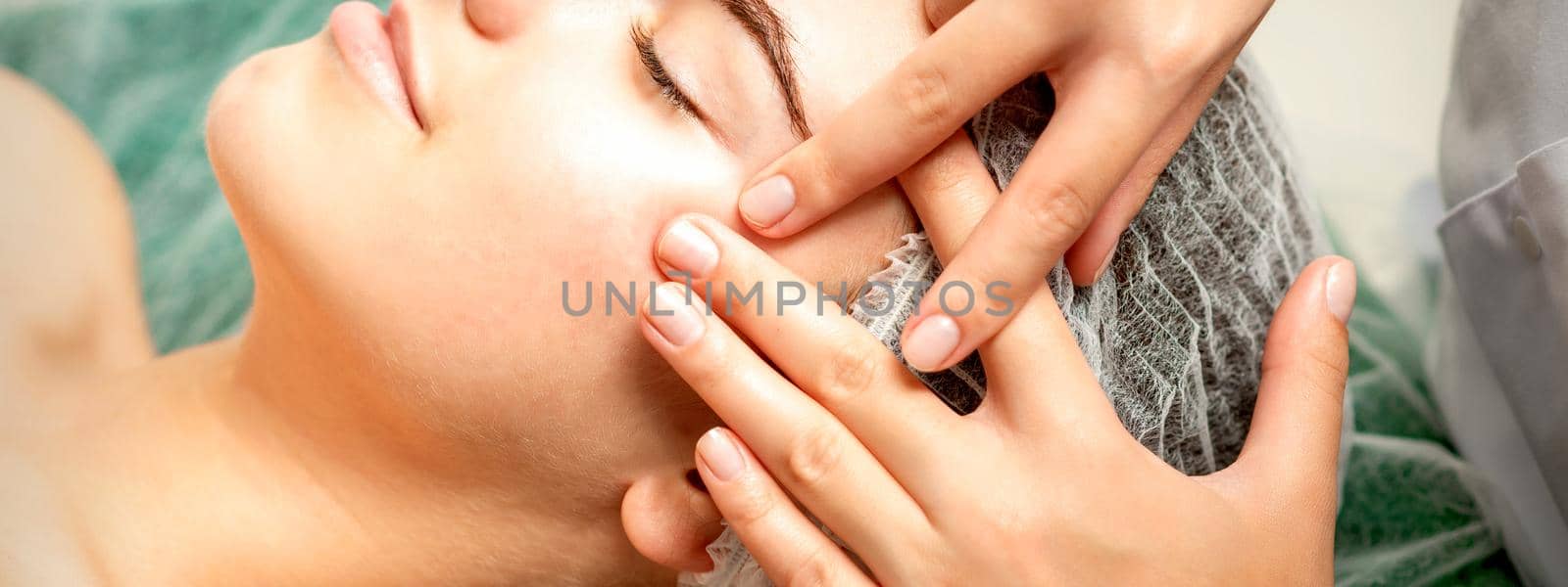 Young woman receiving facial massage by okskukuruza
