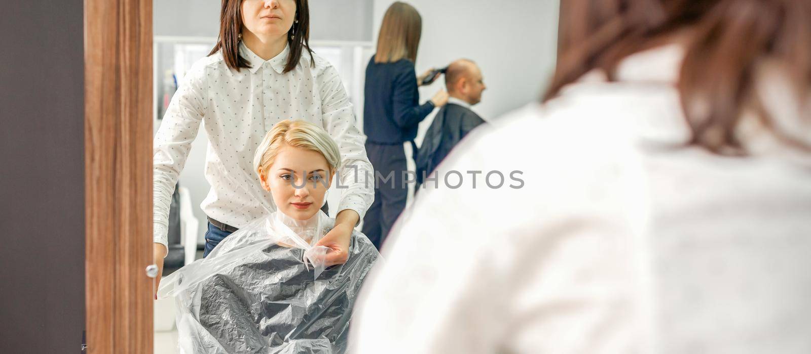 Hairdresser puts on transparent cape by okskukuruza