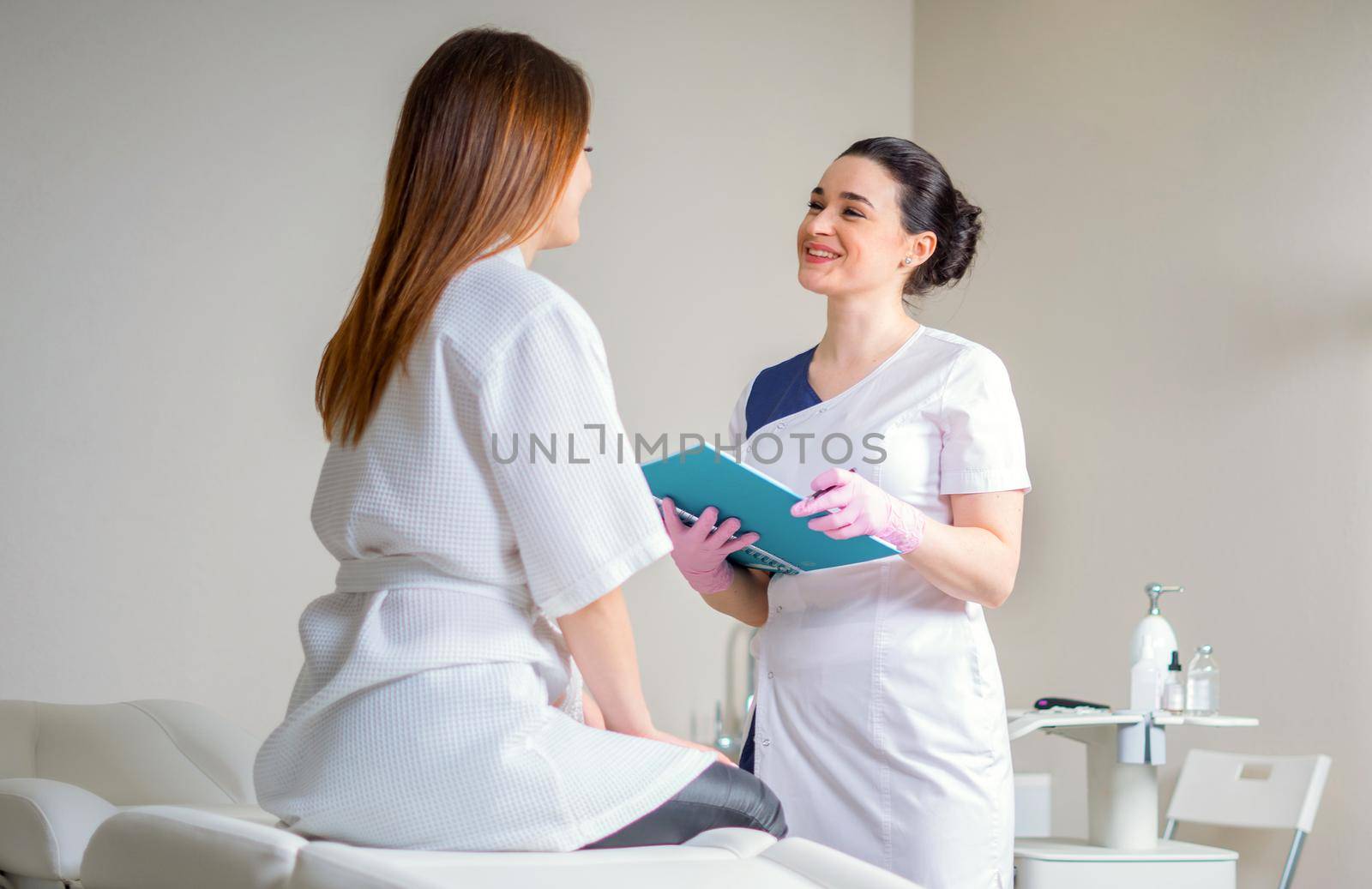 Female Patient And Doctor Have Consultation In medical clinic, writing notes by Mariakray