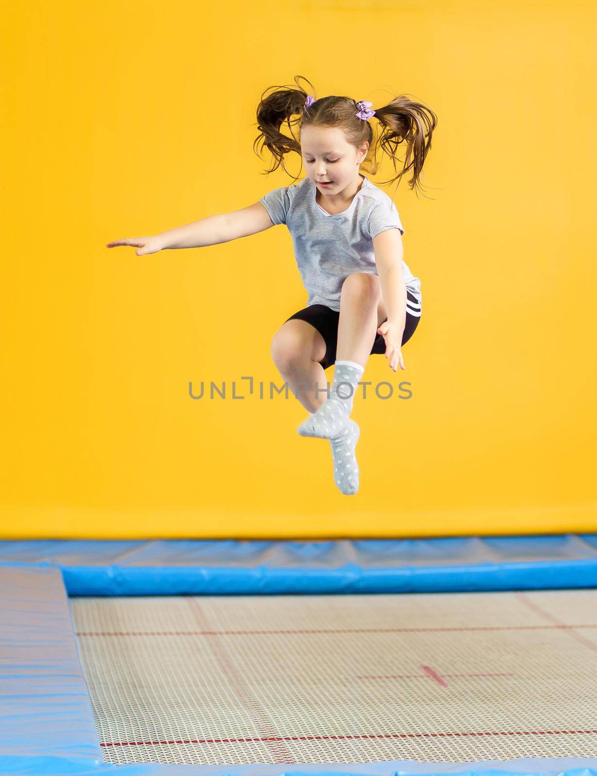 Happy child girl jumping on trampoline in fitness center