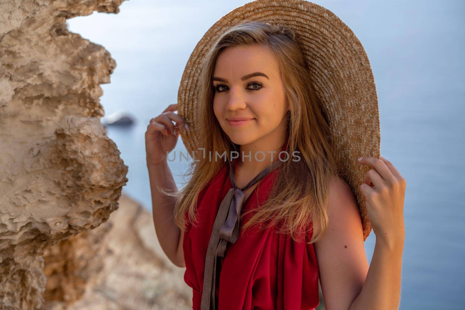 A woman in a red flying dress fluttering in the wind, against the backdrop of the sea. by Matiunina