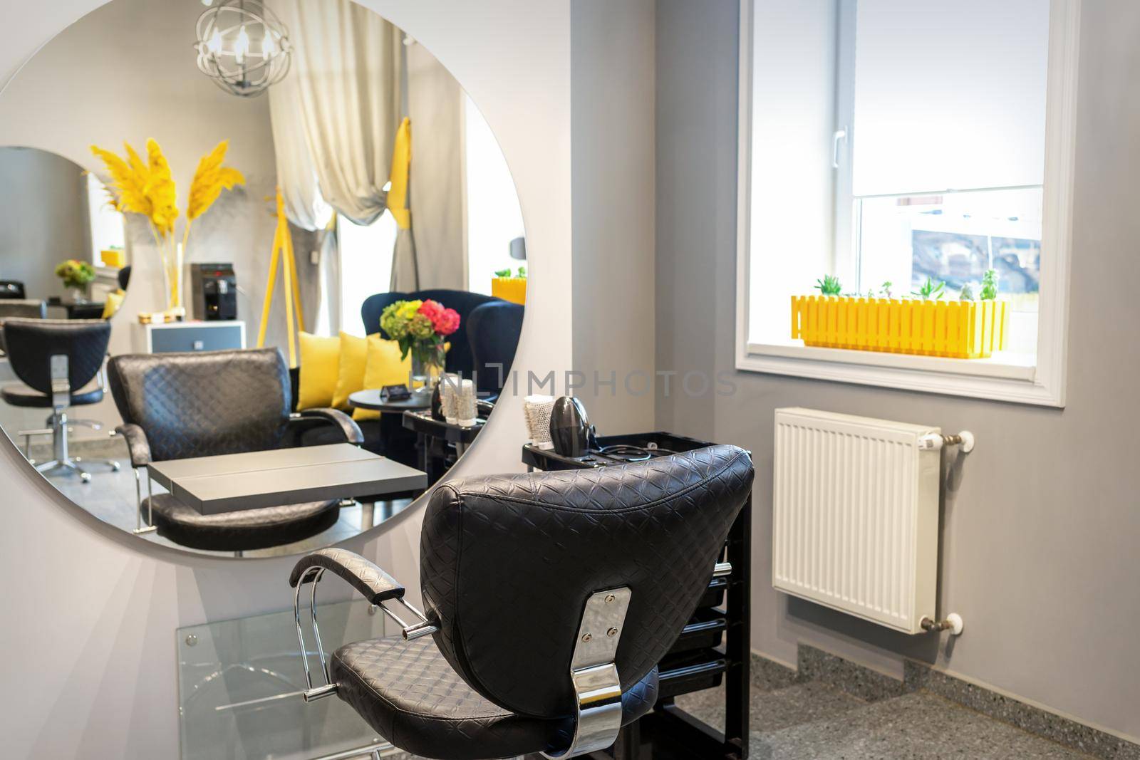 Interior of a beauty salon. Black leather chair in front of the mirror in the beauty salon. Interior of a beauty salon