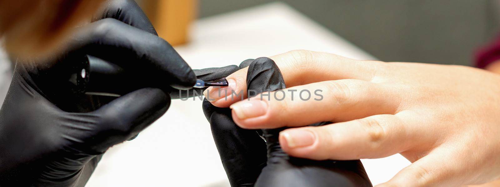 Master covering nails with transparent polish by okskukuruza