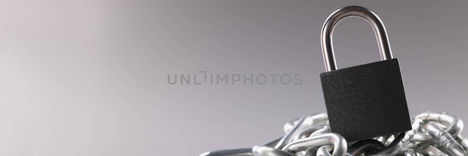 Solid metal locked padlock on top of tangled silver chain by kuprevich