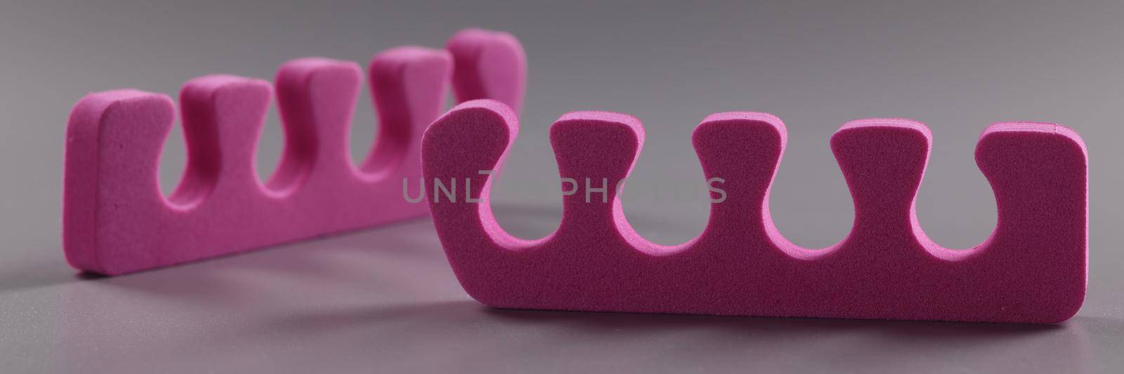 Close-up of pink toe separators, pair of equipment for pedicure procedure. Cute bright cosmetic tools. Pedicure accessory, beauty salon, wellness concept