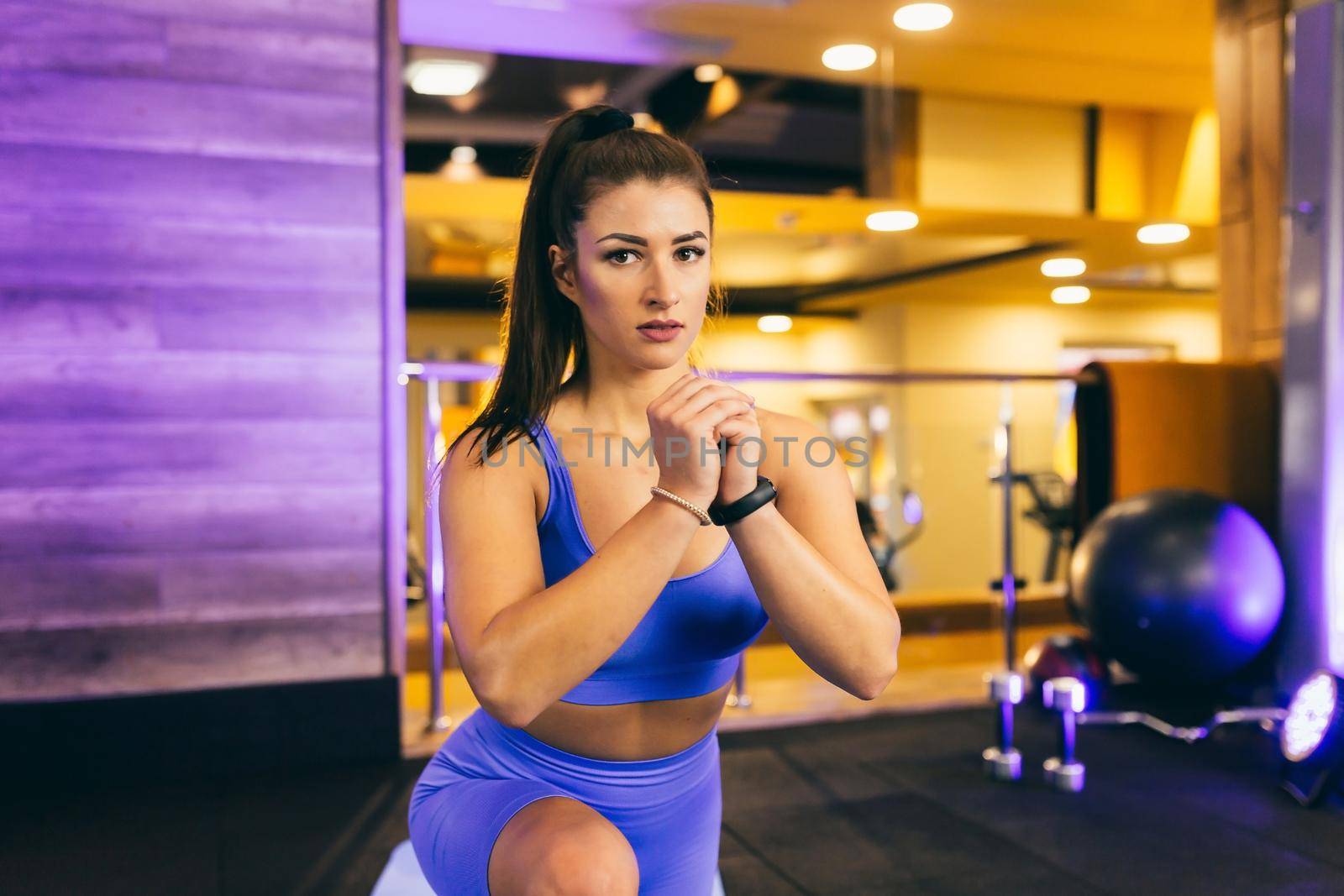 young beautiful sports woman in the gym doing exercises on a mat, in front of a mirror, arm swing, squats, fitness,yoga, in sportswear by voronaman
