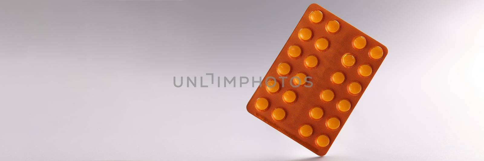 Close-up of blister with tablets, daily dose of medication for person. White tablets in orange package. Prescription, recovery, medicine, health concept