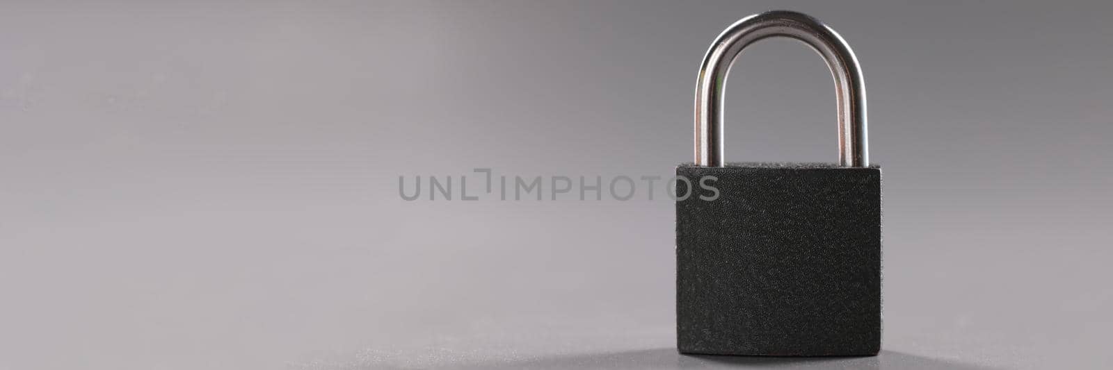 Close-up of solid metal locked padlock on grey background, thing to protect home or apartment. Protection equipment from break in. Safety, security concept