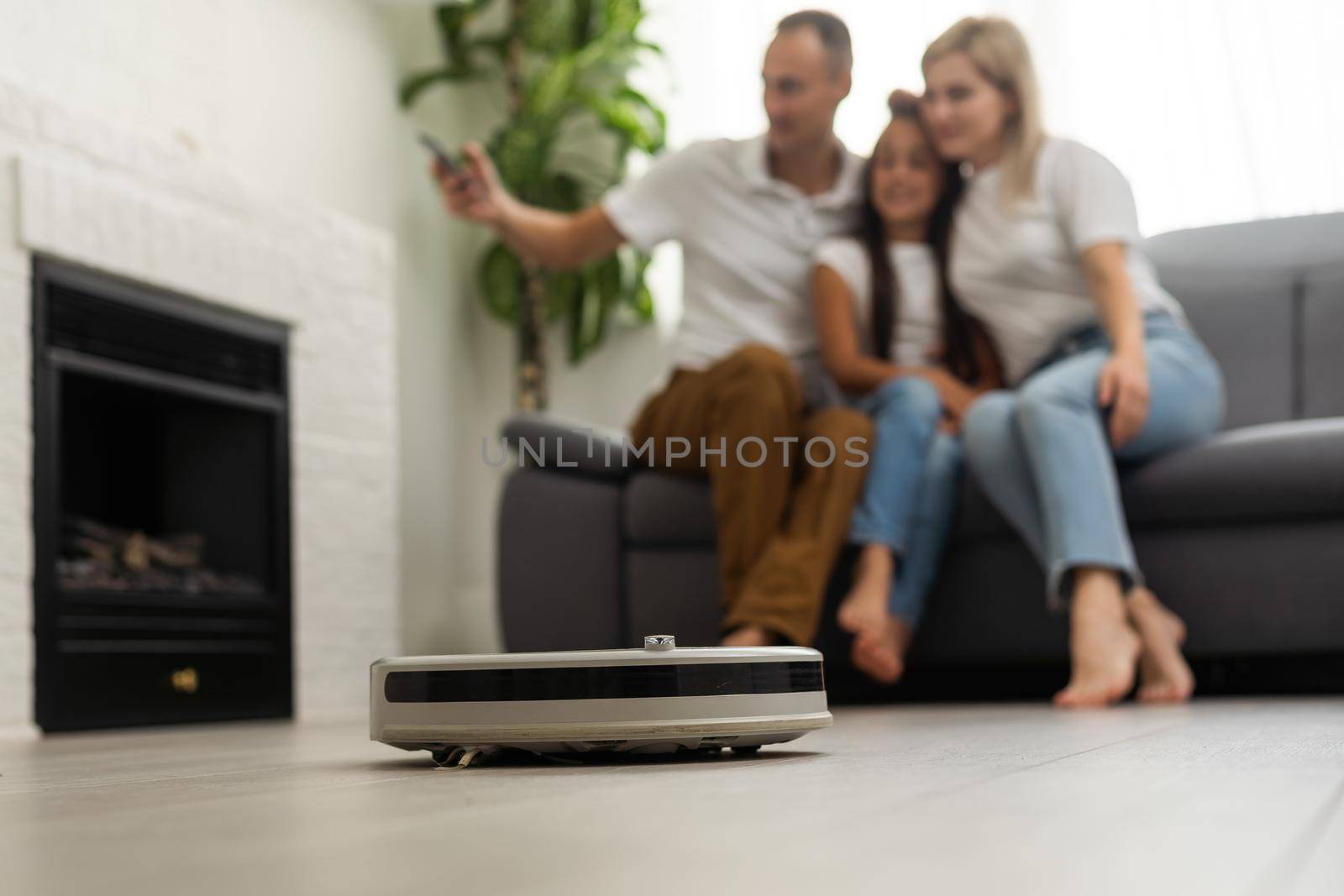 Smiling family pointing at robotic vacuum cleaner.