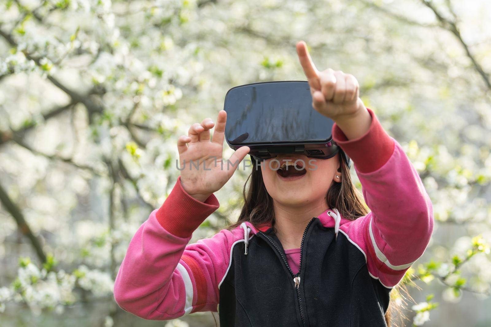 Full body little girl excited and entertained, playing with virtual reality glasses, exploring a fantasy world, trying to touch something. by Andelov13