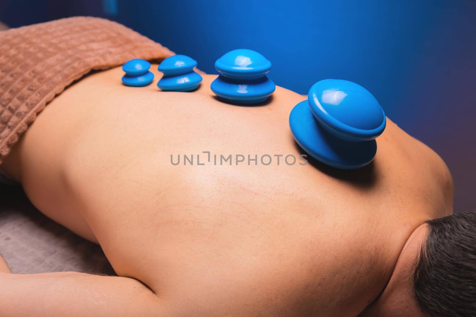 Massage vacuum rubber cans. Close-up of a relaxed man lying with jars on his back in a spa.