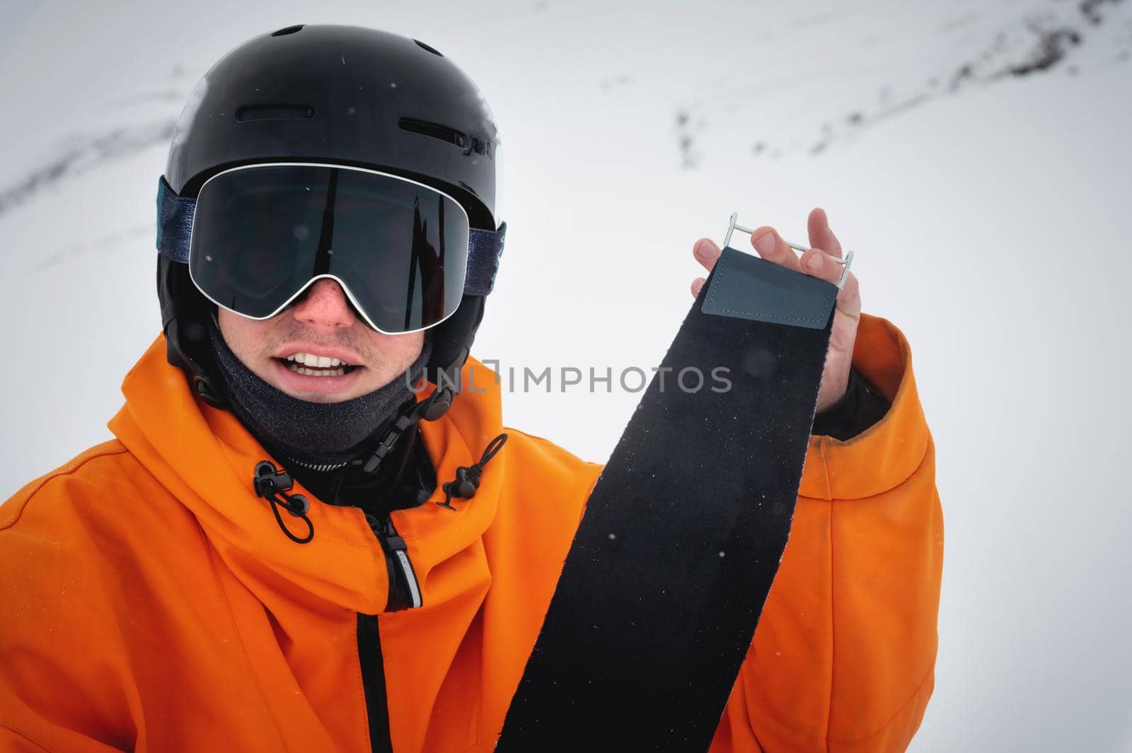 Portrait of a cheerful young caucasian skier at a ski resort against the backdrop of foggy mountains. Winter sports.