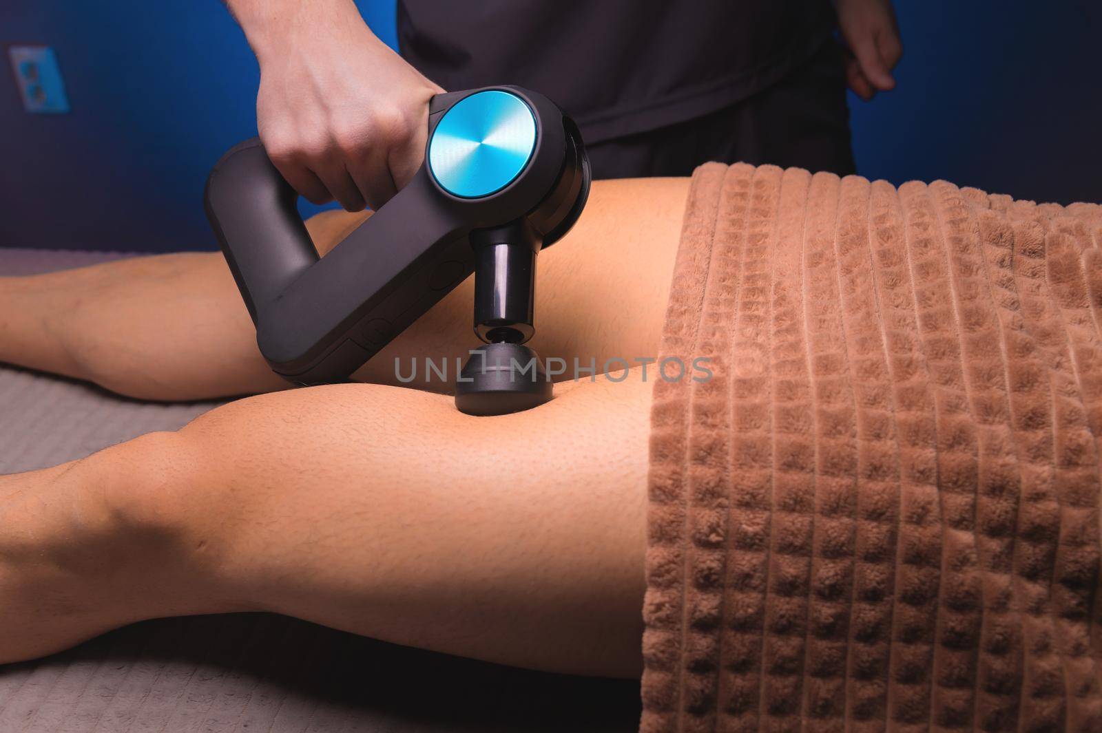 Close-up percussion thigh massage with a special electric device.