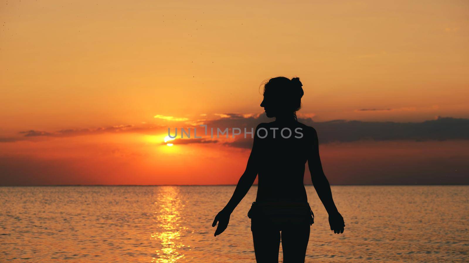 silhouette of woman on the beach at sunset. Young woman relaxing in summer sunset sky outdoor. People freedom style. download photo