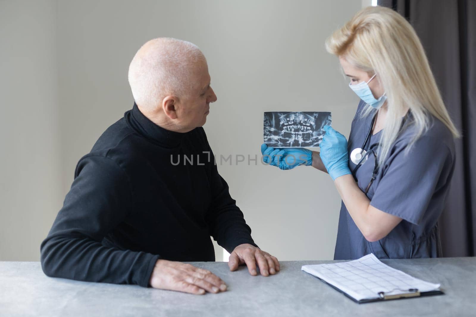 Dental Clinic. An elderly retired gentleman, discussing with his dentist radiography (x-ray) results