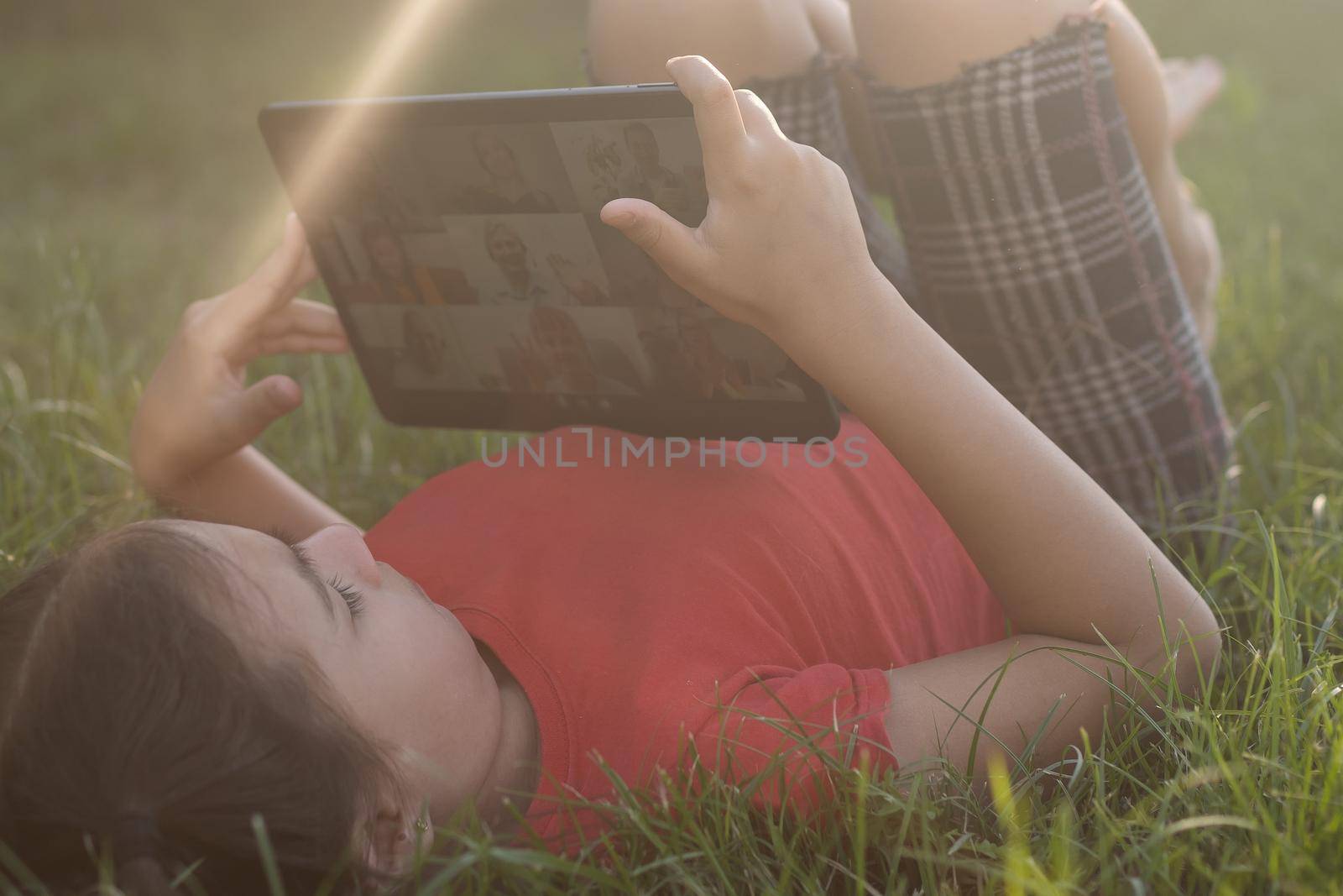 Girl on the grass with a tablet chat in her hands in the garden.