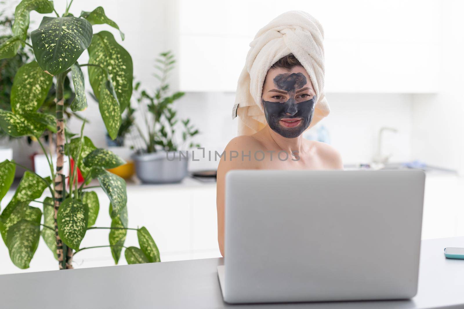 incredible pretty girl at home in pajamas made a cosmetic mask and works with a laptop. The concept of cosmetic mask on a girl. by Andelov13