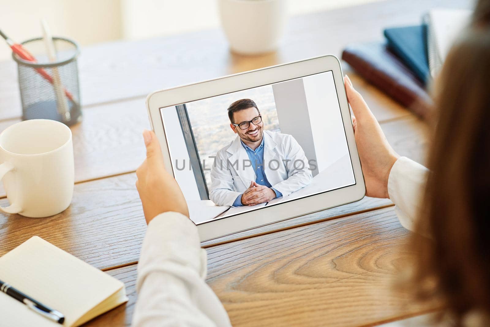 Back view of a woman making video call with her doctor while staying at home