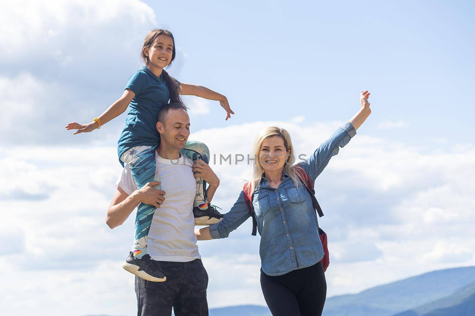 Family hiking parents with child outdoor travel in mountains active vacations lifestyle mother and father backpacking together. by Andelov13