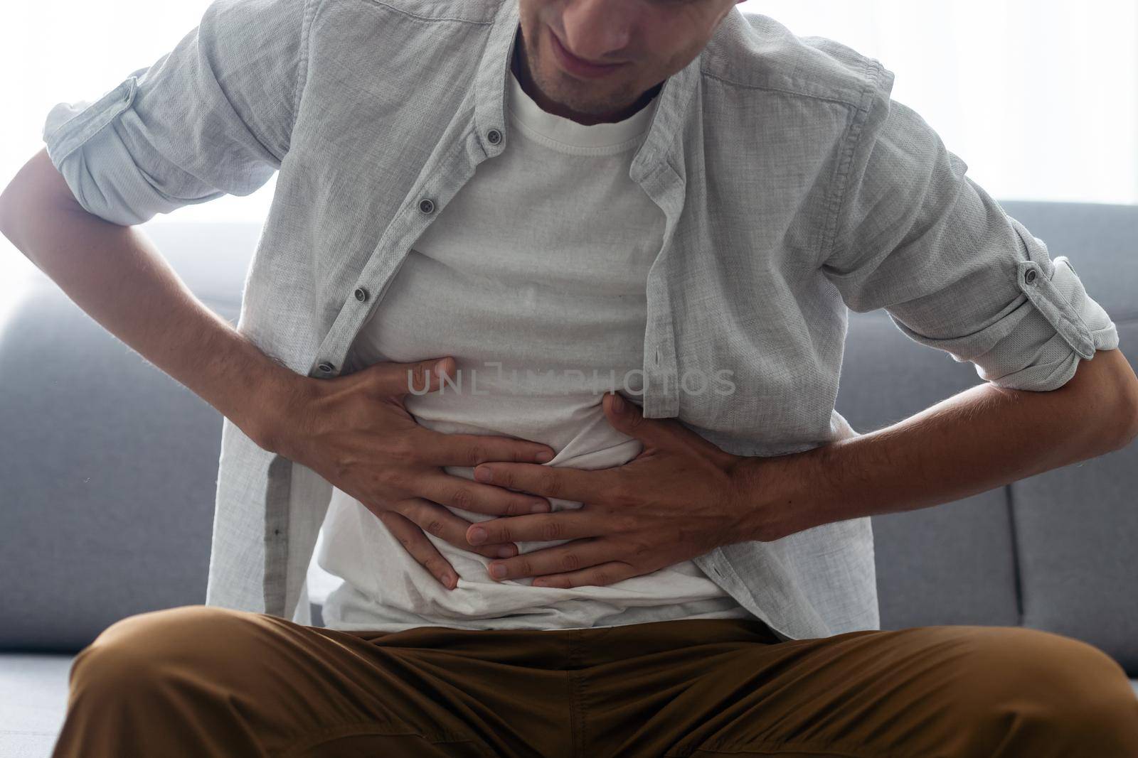 Cropped close up studio photo portrait of upset sad scared worried troubled gut having stomach ache disorder wear denim pants isolated grey background