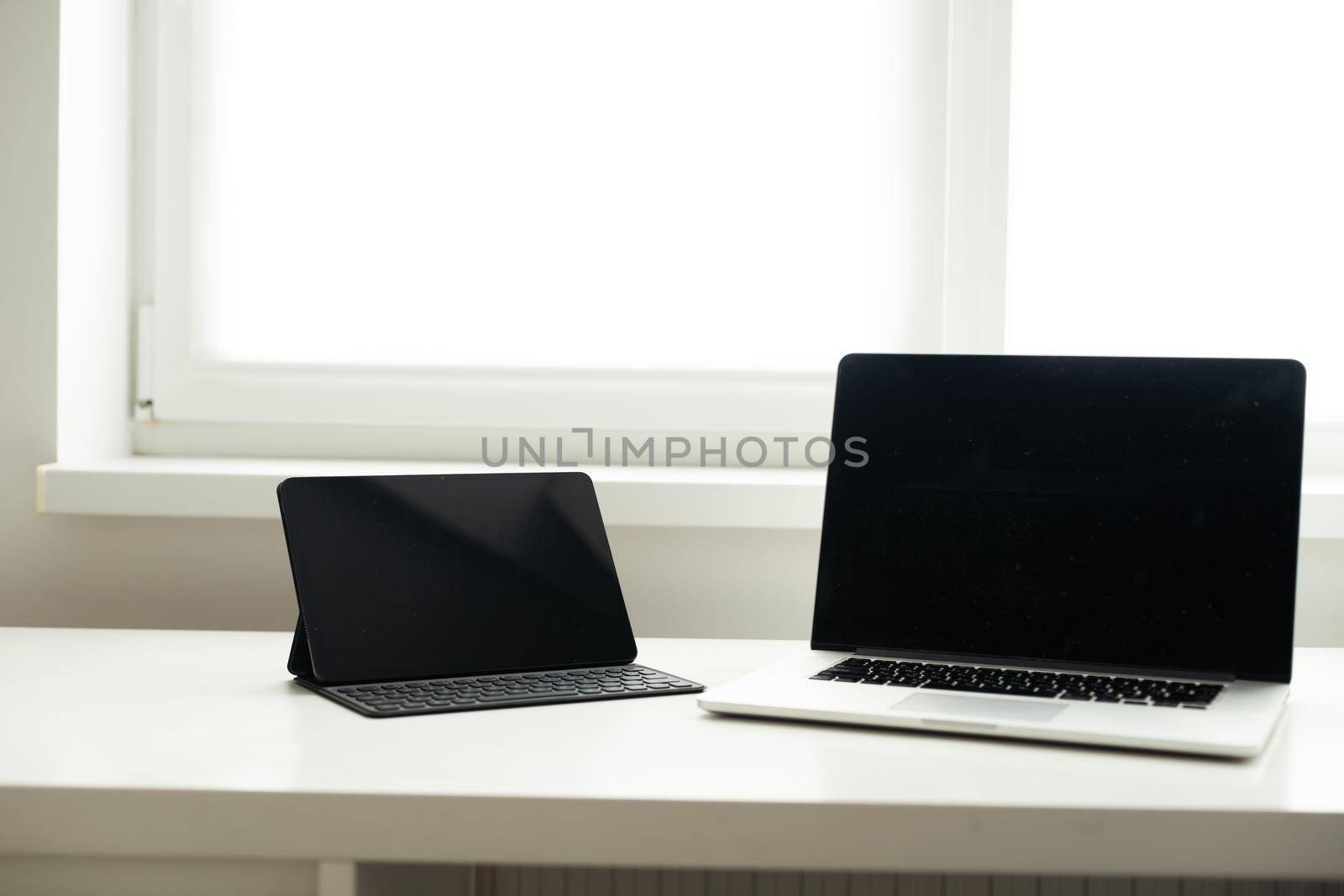 laptop and tablet on a white table. by Andelov13