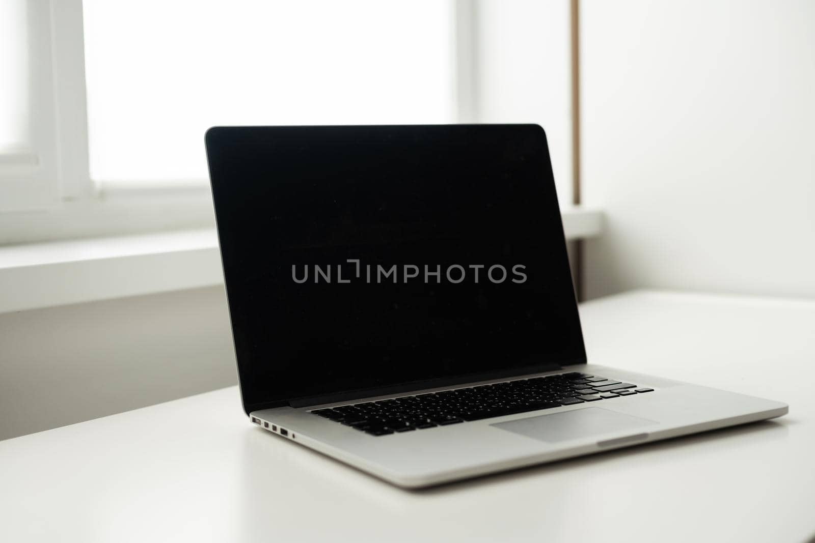 modern workspace with blank screen laptop on white table with white wall background.