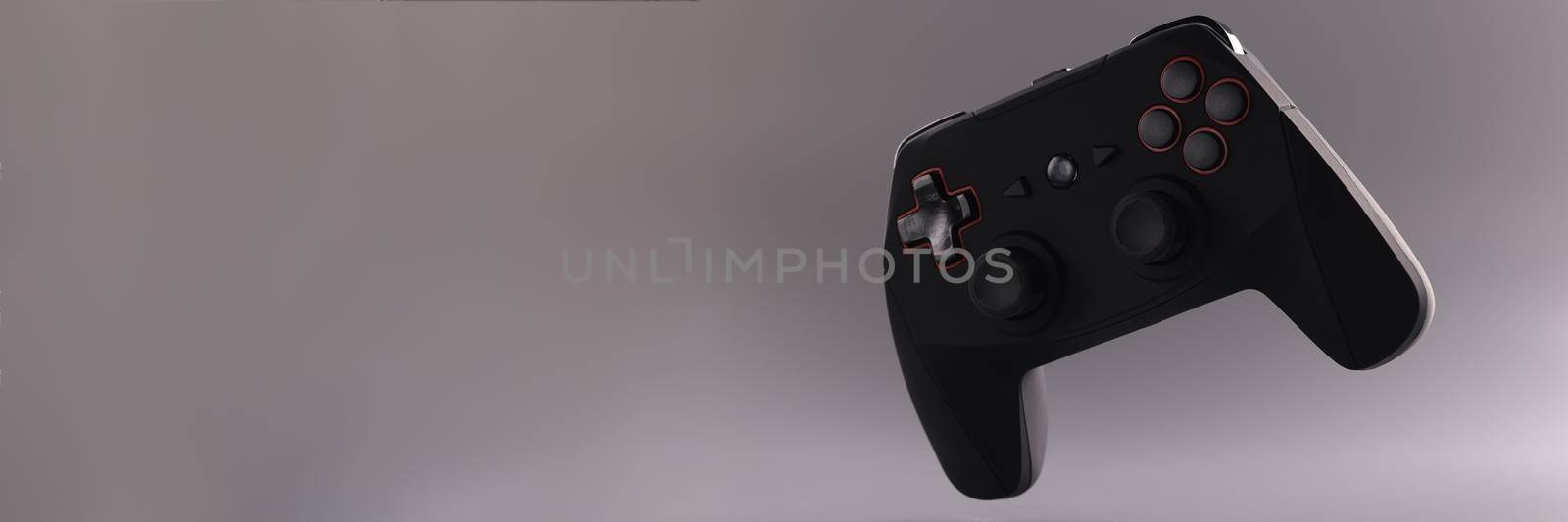 Close-up of black video game joystick or gamepad floating in air. Single game console on grey background. Gamer, competition, addiction, online concept