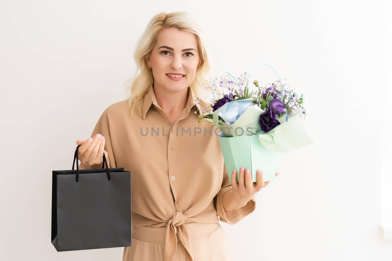 Woman holding blank black craft package, mock-up of black paper bag with handles.