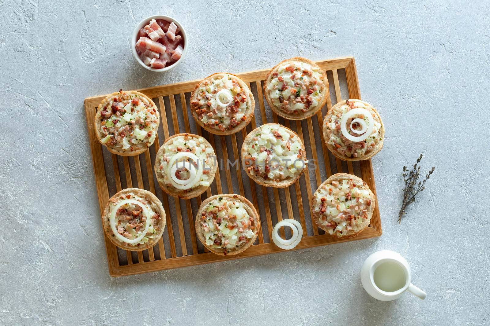 mini portions of flammekueche, or tarte flambee, french and german speciality, on the wooden cooling grid, top view