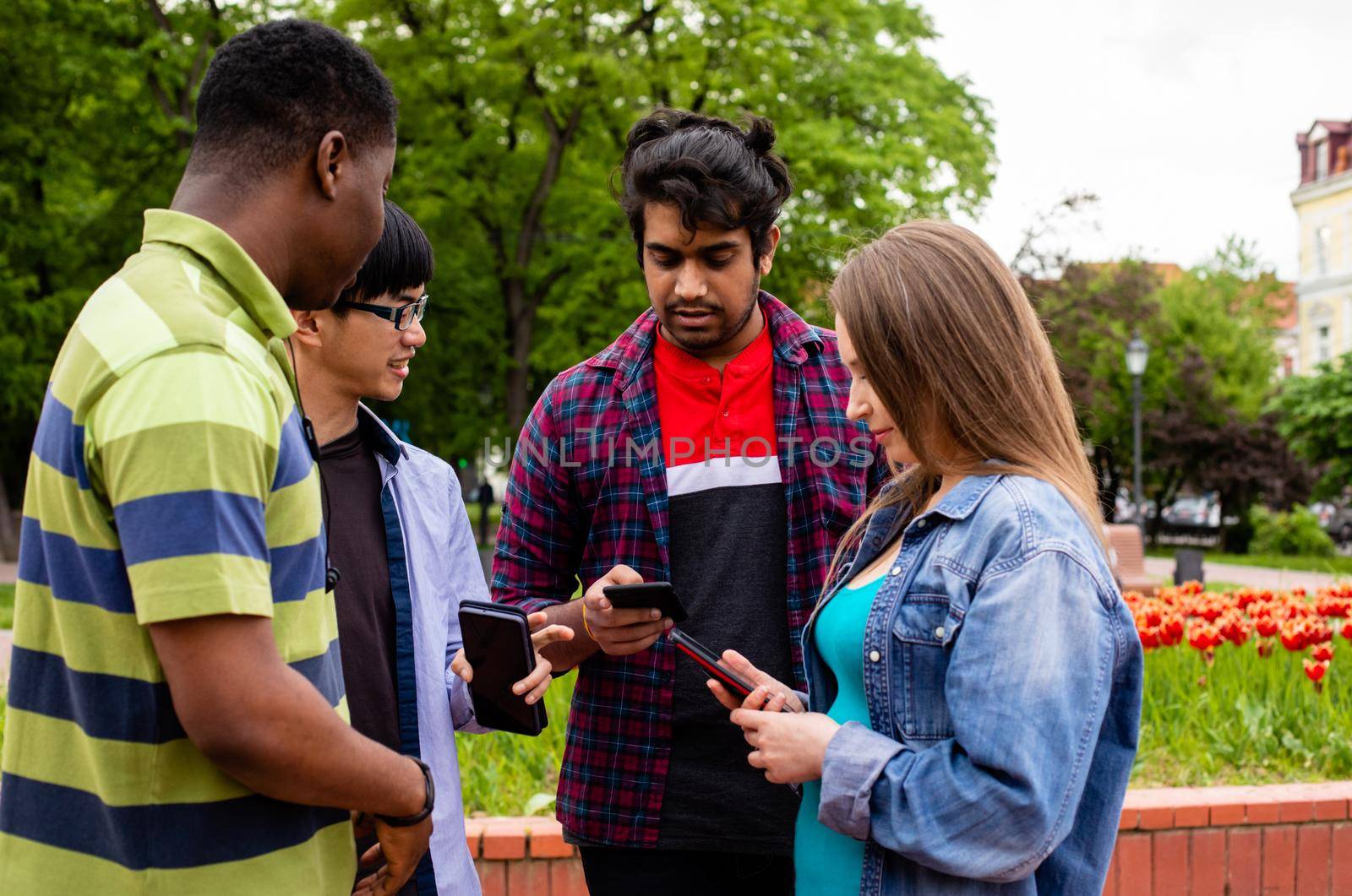 College students having great time together after lessons. Young people can't live without their smartphones, checking massages during meeting with friends. Gadgets addiction concept.