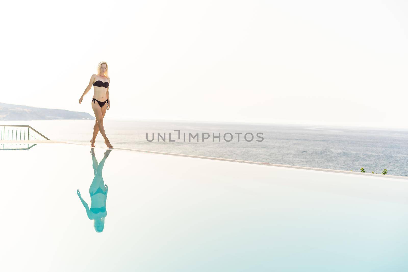 woman relaxing near swimming pool by Andelov13