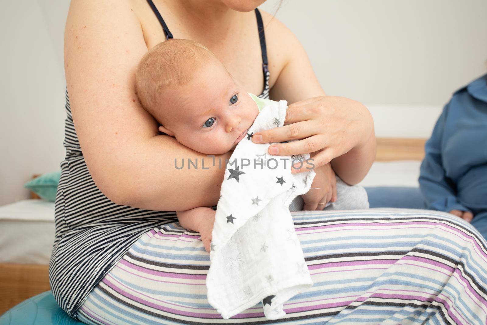 Mother rocks newborn baby sitting on fitball. New lifestyle with asleep newborn at bedroom