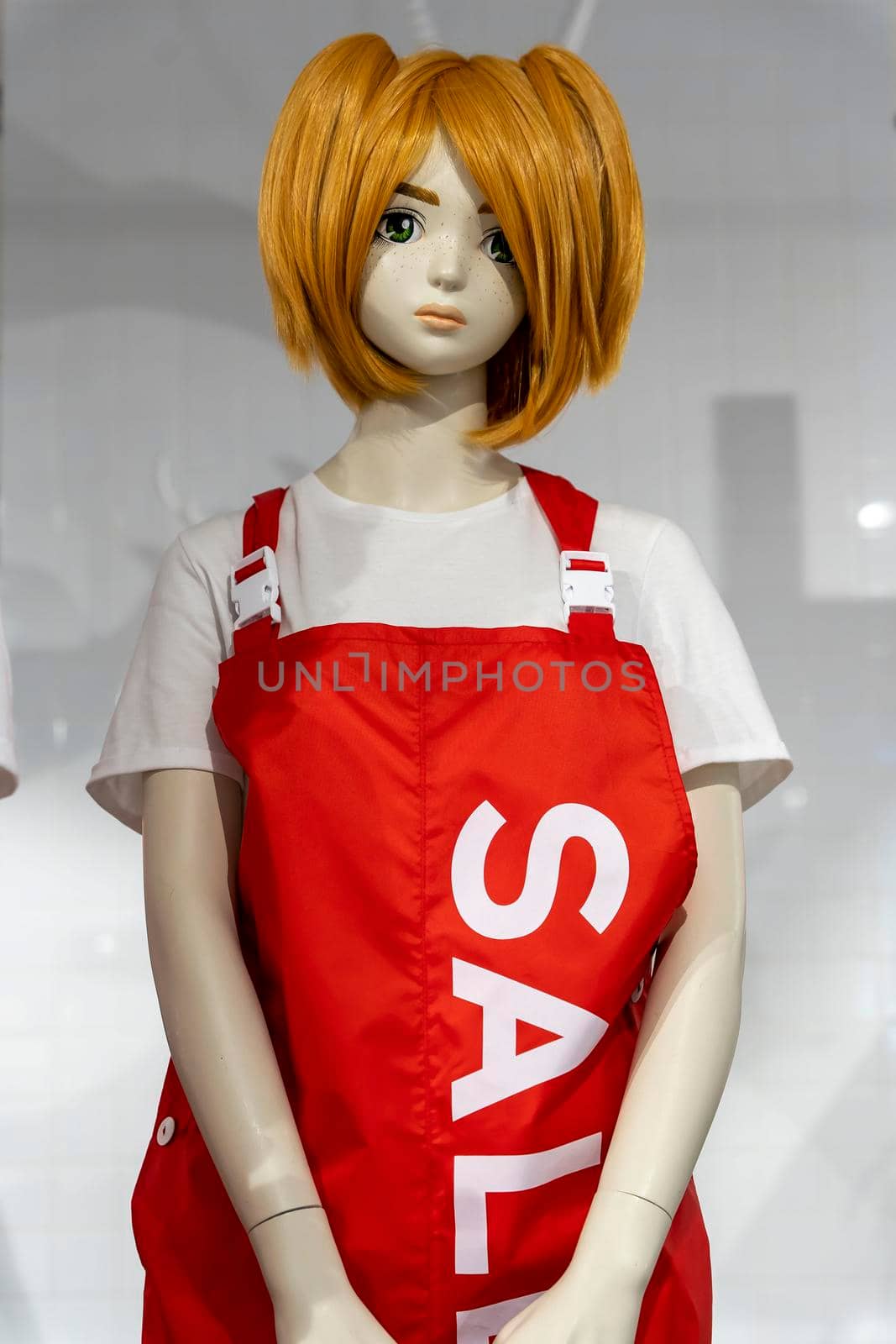 beautiful mannequin girl in a seller's apron with red hair in a clothing store. shopping, fashion, style. Standing woman dummies show collection of clothes